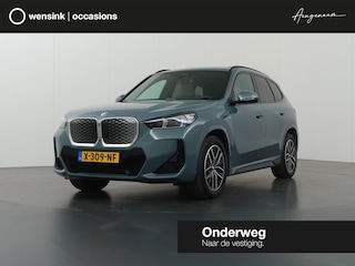 BMW iX1 eDrive20 67 kWh M-Pakket | SOH 98% | Panormadak | Sportstoelen | Curved Display | Harman/Kardon | Camera | Apple CarPlay/Android Auto | Ele.verstelbare stoelen + Geheugen | Ele. kofferdeksel |